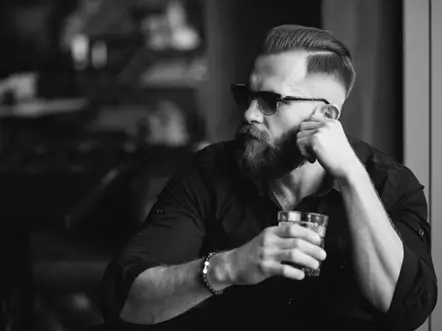 handsome male model at a bar wearing sunglasses and holding a drink